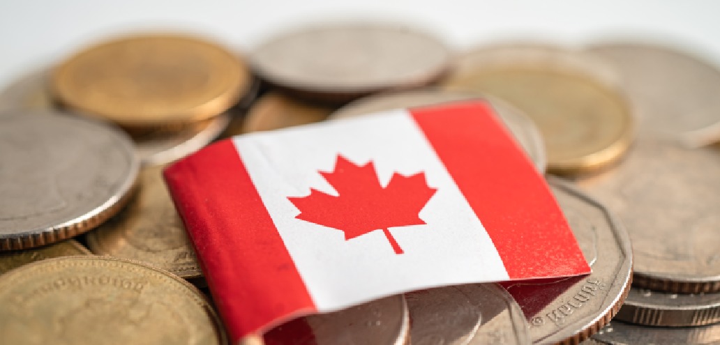 A small Canadian flag lies on a pile of various coins.